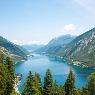 Alpine lake with fir trees and distant mountains in Tyrol, Austria